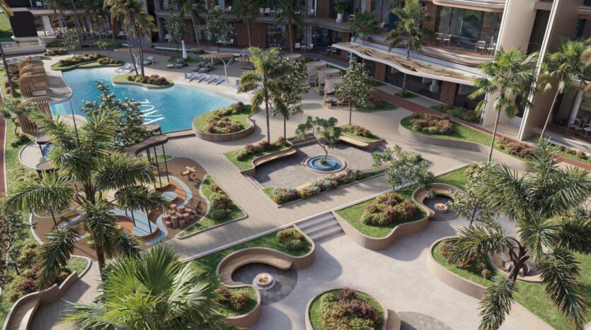 Au Mirari Lagoon by Zoya, au milieu de bâtiments modernes, vous découvrirez une cour paysagée agrémentée de palmiers, de bancs incurvés, d'une fontaine centrale, de pelouses, d'allées et d'une piscine avec des transats.
