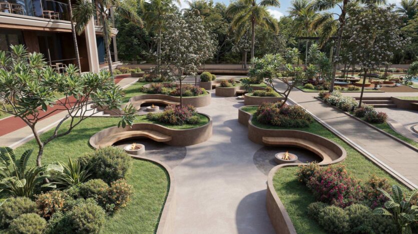 Une cour-jardin aménagée, agrémentée de bancs incurvés, de parterres de fleurs, d'arbres et d'allées, entourée de palmiers et d'un bâtiment sur la gauche, évoque l'ambiance paisible de la lagune Mirari signée Zoya.