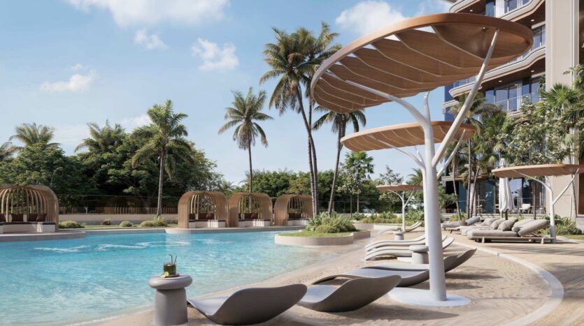 L'espace luxueux au bord de la piscine du Mirari Lagoon by Zoya propose des chaises longues modernes, de grands auvents en forme de feuille, des palmiers et des cabines privées, le tout situé à côté d'un superbe bâtiment de complexe hôtelier, sous un ciel ensoleillé.