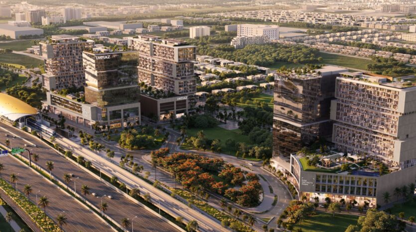 Vue aérienne du quartier Raw 2, photographiée par Imtiaz, mettant en valeur un complexe urbain moderne composé d'immeubles de bureaux vitrés, de routes bordées d'arbres, d'une végétation luxuriante et d'une grande autoroute à proximité. Des zones résidentielles et des espaces verts s'étendent à l'arrière-plan.