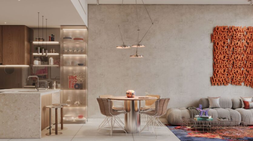 Cuisine ouverte moderne avec coin repas dans le quartier Raw District 2, conçue par Imtiaz, avec des plans de travail beiges, des étagères en verre, une table à manger ronde entourée de chaises en fil de fer et un espace de vie chaleureux. Une décoration murale orange reprend en boucle le texte « HAPPILY EVER AFTER ».