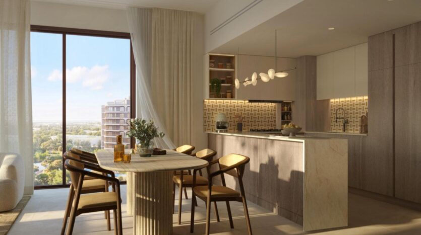 Cuisine et coin repas modernes aux finitions en bois et en marbre au complexe « The Canopies by Aldar », comprenant six chaises disposées autour d'une table, de grandes baies vitrées offrant une vue sur la ville et la verdure, ainsi que des suspensions au-dessus de l'îlot central.