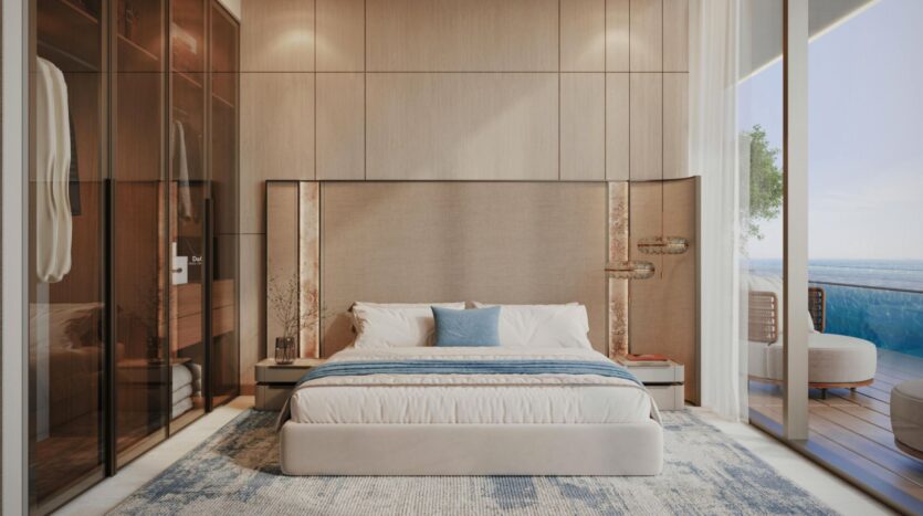 Chambre moderne dotée d'un grand lit, d'une parure de lit bleue et blanche, de murs lambrissés, d'une armoire vitrée et de baies vitrées s'ouvrant sur un balcon offrant une vue imprenable sur la mer depuis la « Vue Dorée ».