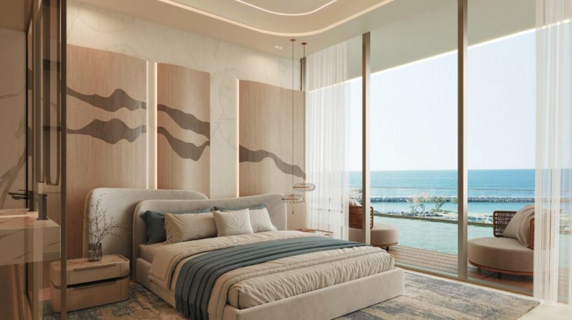 Chambre moderne dotée d'un grand lit, de tons neutres, d'une décoration murale élégante, de baies vitrées et d'une vue sur l'océan à la résidence Vue Dorée. Un balcon aménagé d'un coin salon invite à la détente, tandis que la lumière naturelle inonde cet espace à la fois chaleureux et raffiné.