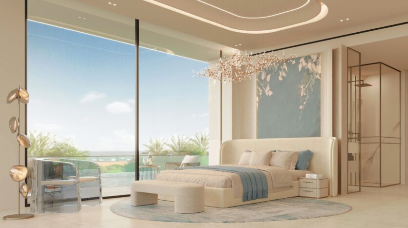 Chambre luxueuse dotée de grandes fenêtres, d'un lustre moderne, de tons neutres, d'un mur d'accent bleu et d'une vue sur la piscine au Vue Dorée. Une chaise et un bureau en acrylique, un banc au pied du lit et un éclairage tamisé créent une atmosphère élégante et sereine.